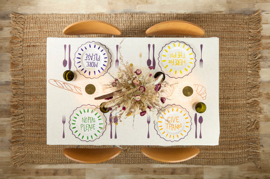 Aerial view looking down on a rectangle table with four chairs. Table has white tablecloth with painted features, dried floral centerpiece and painted plates