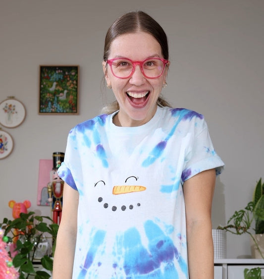 woman with smiling face wearing a blue tie dye snowman shirt