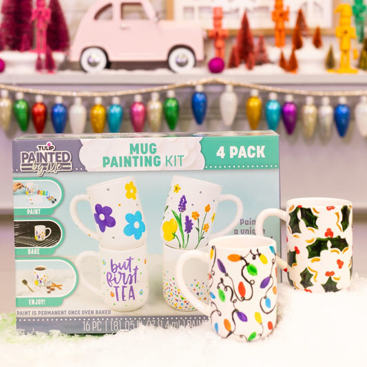 Mug painting kit with four decorated mugs and packaging in a festive setting.