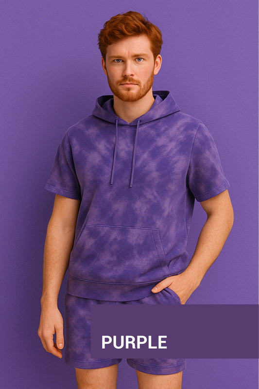 Man wearing a purple tie-dye hoodie and shorts set against a purple background.