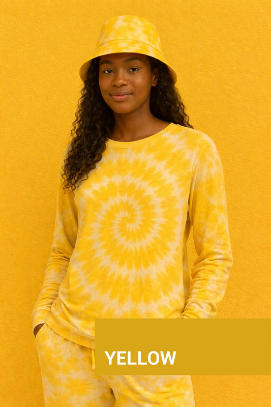 Person wearing a yellow tie-dye outfit with a matching hat against a yellow background