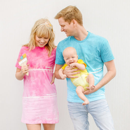 Family of three wearing matching colorful t-shirts against a white background