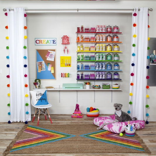Colorful craft room with shelves, a dog on a pillow, and a rainbow rug.